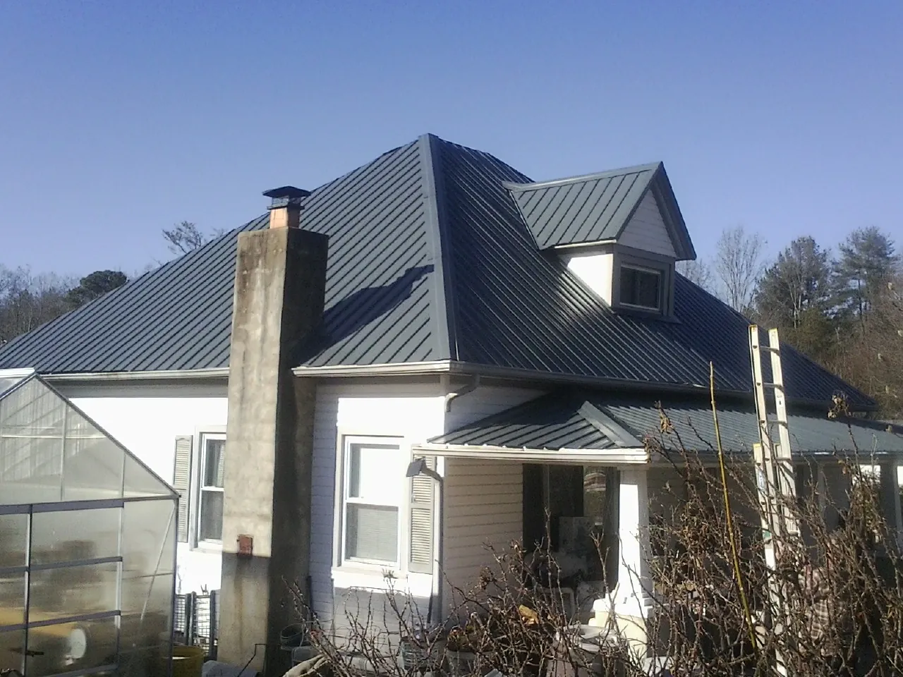 Dark blue standing seam metal roof on a white farmhouse with dormer — Slate & Tile Roof Repair by Roofing Brothers in Mount Pulaski