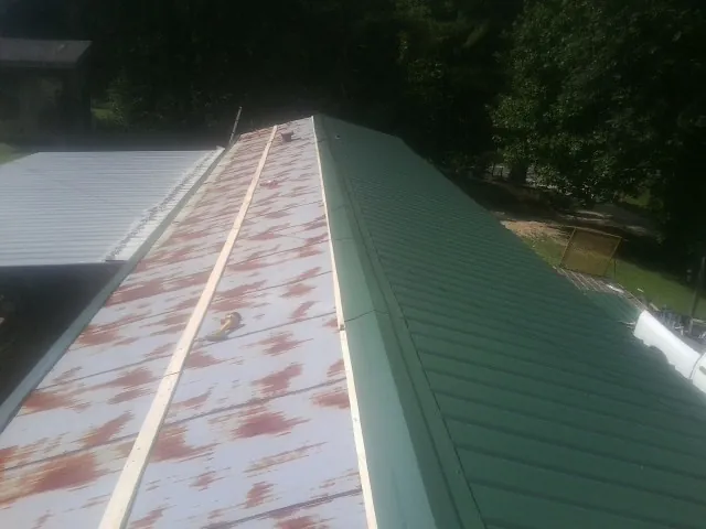 Old rusted panels beside newly installed green metal roofing — Wind Damage Roof Repair by Roofing Brothers in Mount Pulaski