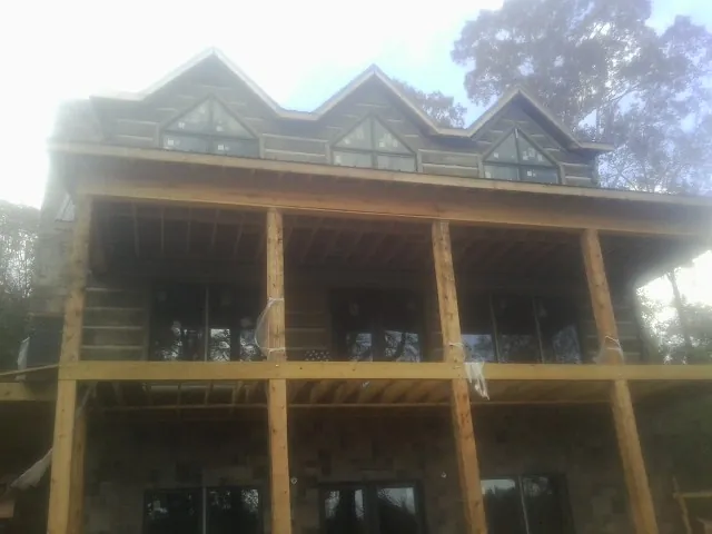 Dormers and porch framing on a large log home under construction — Roof Coating work by our crew in Mount Pulaski