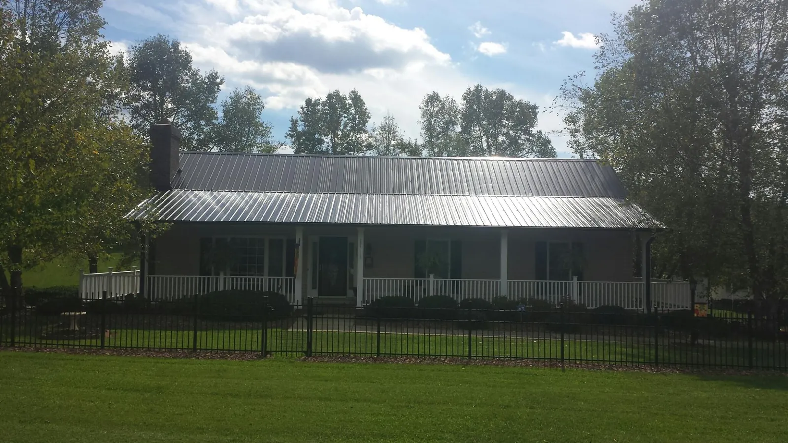 Gray metal roof on a brick ranch with a full width front porch — Gutter Guard Installation work by our crew in Mount Pulaski