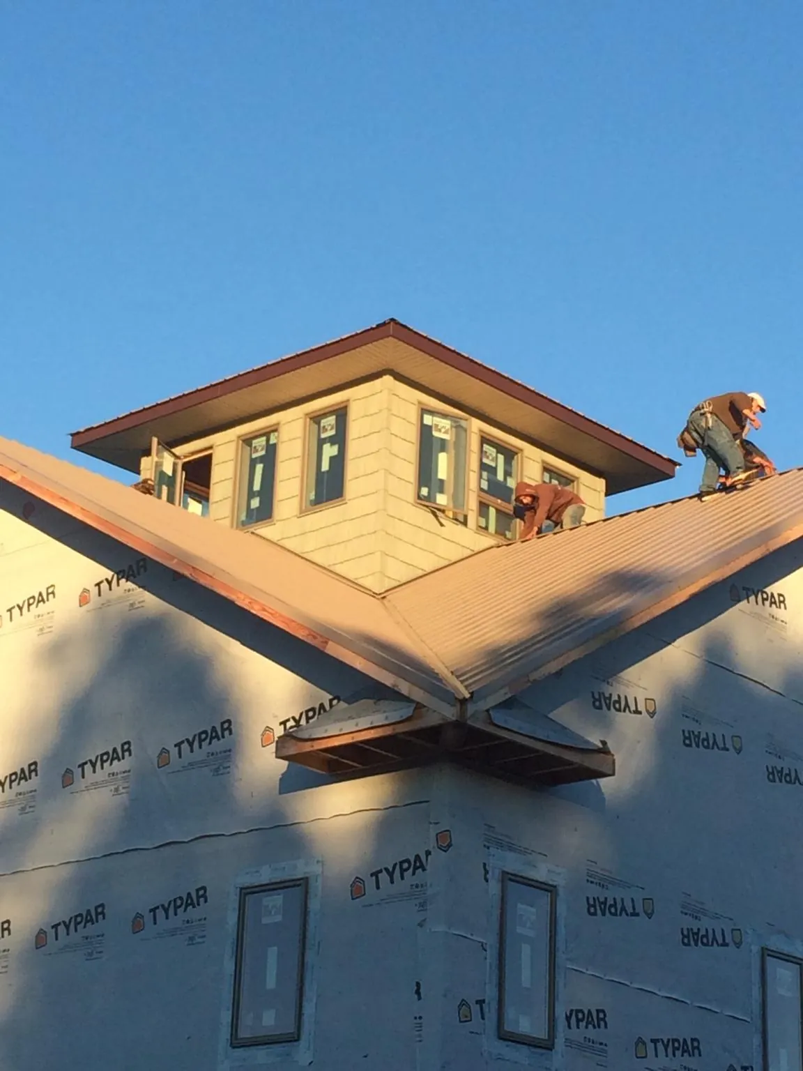 Roofers working around a rooftop cupola on a new metal roof at sunset — Roof Waterproofing in Mount Pulaski by Roofing Brothers